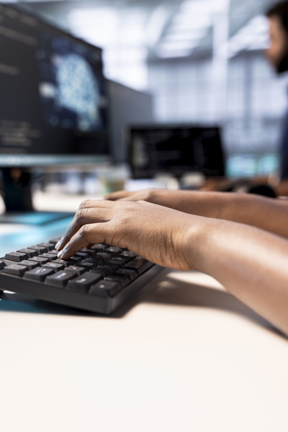 Dłonie na klawiaturze przy biurku z monitorem