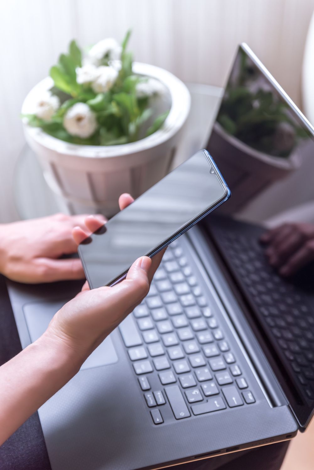 Telefon służbowy w dłoni nad laptopem