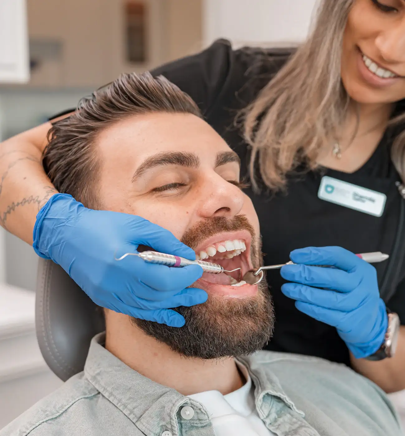 Dentystka rozmawia z uśmiechniętym pacjentem na fotelu